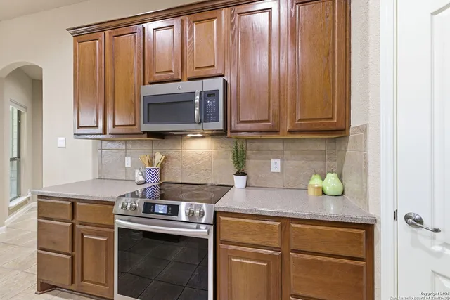 a kitchen with kitchen island granite countertop a stove top oven a sink a counter top space and cabinets