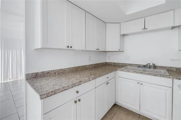 a kitchen with granite countertop white cabinets and a sink