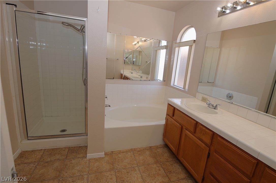 8220 Maplestar Road Las Vegas, NV 89128 - Photo 17 of 29 A well-appointed bath features a dedicated shower, a deep soaking tub, and a vanity with abundant counter space.
