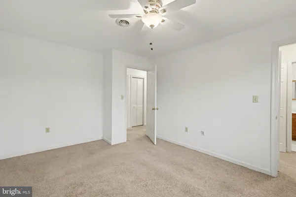 an empty room with chandelier fan and closet area
