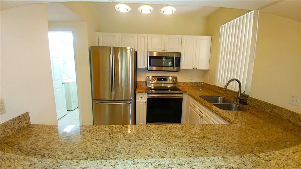 6640 West Sample Road, Unit 6640 Coral Springs, FL 33067 - Photo 6 of 25 a kitchen with granite countertop a refrigerator and a sink