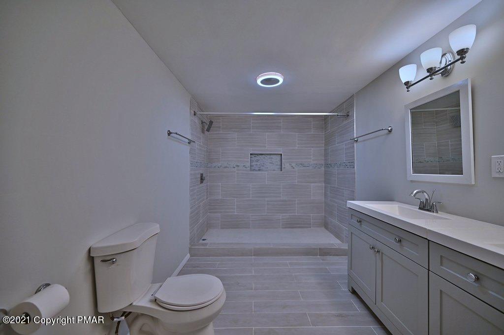 102 Forest Road Dingmans Ferry, PA 18328 - Photo 28 of 75 a bathroom with a granite countertop sink toilet a mirror and shower