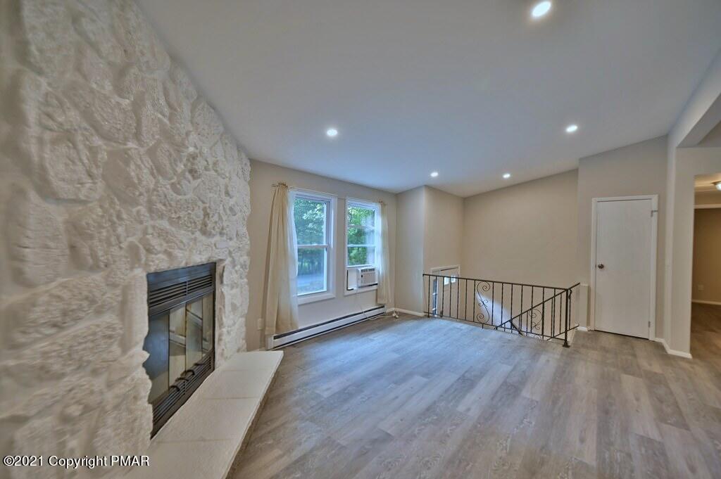 102 Forest Road Dingmans Ferry, PA 18328 - Photo 3 of 75 an empty room with wooden floor fireplace and windows