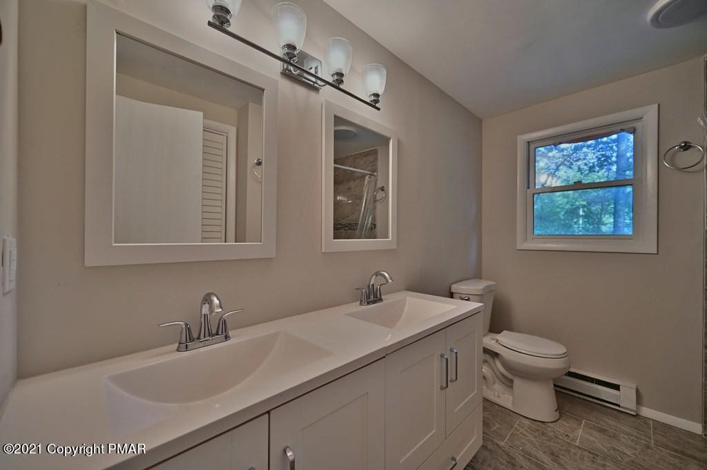 102 Forest Road Dingmans Ferry, PA 18328 - Photo 39 of 75 a bathroom with a toilet a sink a mirror and a window
