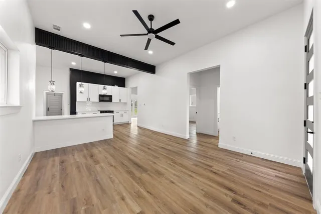 a view of an empty room with window and wooden floor
