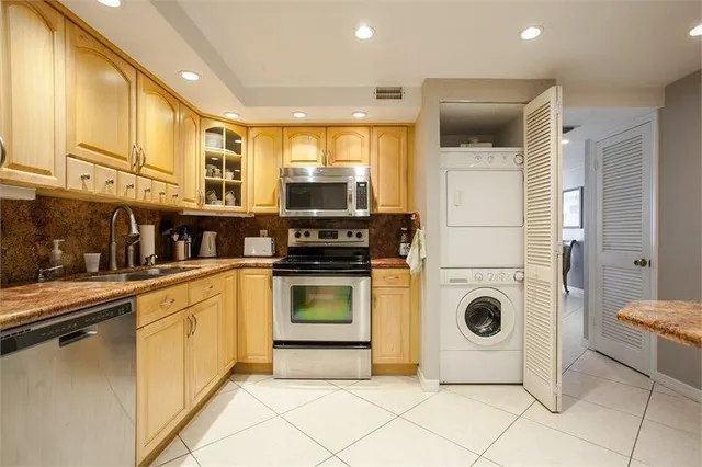 a kitchen with stainless steel appliances kitchen island granite countertop a refrigerator and a stove top oven