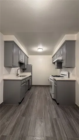 a kitchen with stainless steel appliances granite countertop a stove a sink dishwasher and a refrigerator with wooden floor