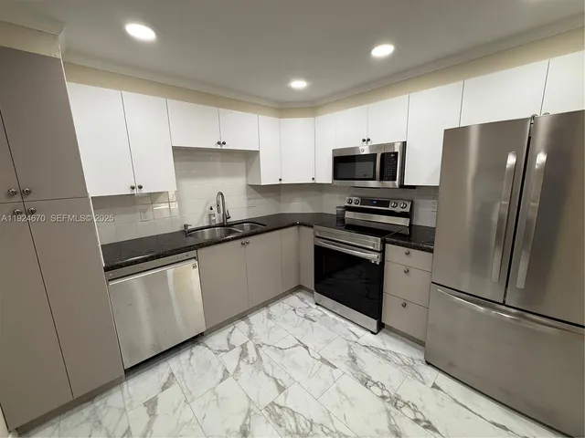 a kitchen with granite countertop a refrigerator sink and wooden cabinets