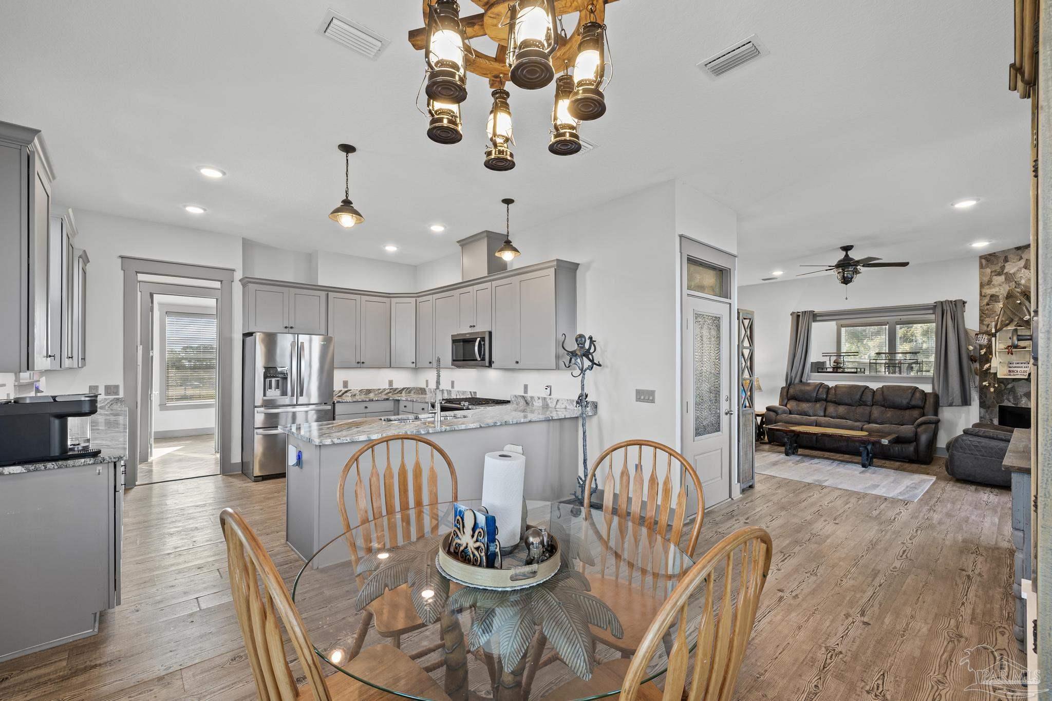 305 Garcon Point Road Milton, FL 32583 - Photo 19 of 72 a kitchen with stainless steel appliances granite countertop a dining table chairs stove and white cabinets