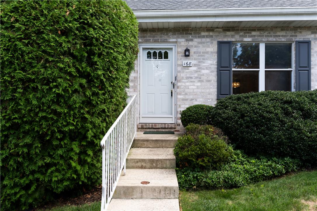 168 Springhouse Road Allentown, PA 18104 - Photo 5 of 49 A welcoming entry features a light brick facade, white door, and meticulously maintained shrubbery creating inviting curb appeal.