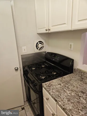 a kitchen with granite countertop white cabinets and black appliances
