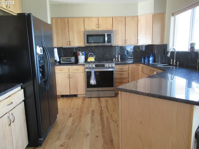 a kitchen with stainless steel appliances granite countertop a refrigerator a stove top oven a sink and dishwasher