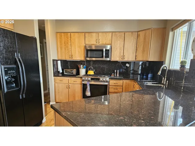 a kitchen with stainless steel appliances kitchen island granite countertop a refrigerator a stove top oven a sink and dishwasher