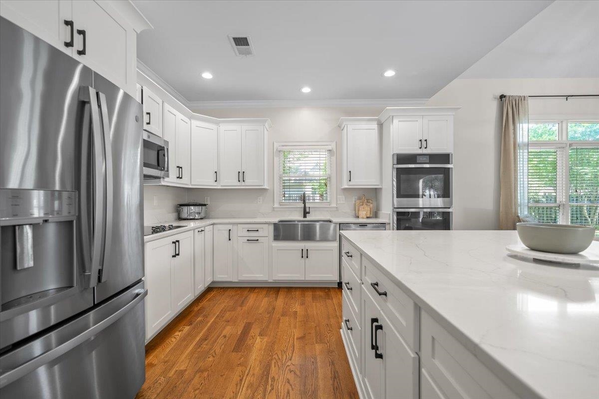 1876 Liles Lane Collierville, TN 38017 - Photo 4 of 36 Contemporary kitchen featuring white cabinetry, stainless steel appliances, a large center island with a white countertop, recessed lighting, and wood-finish flooring
