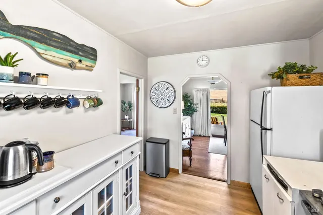 a view of a kitchen with fridge and wooden floor