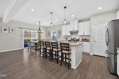 a kitchen with stainless steel appliances granite countertop a refrigerator a stove top oven a island with wooden floor and cabinets