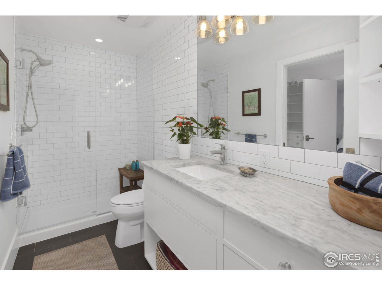 3858 57th Street Boulder, CO 80301 - Photo 21 of 39 a bathroom with a granite countertop sink a toilet a mirror and shower
