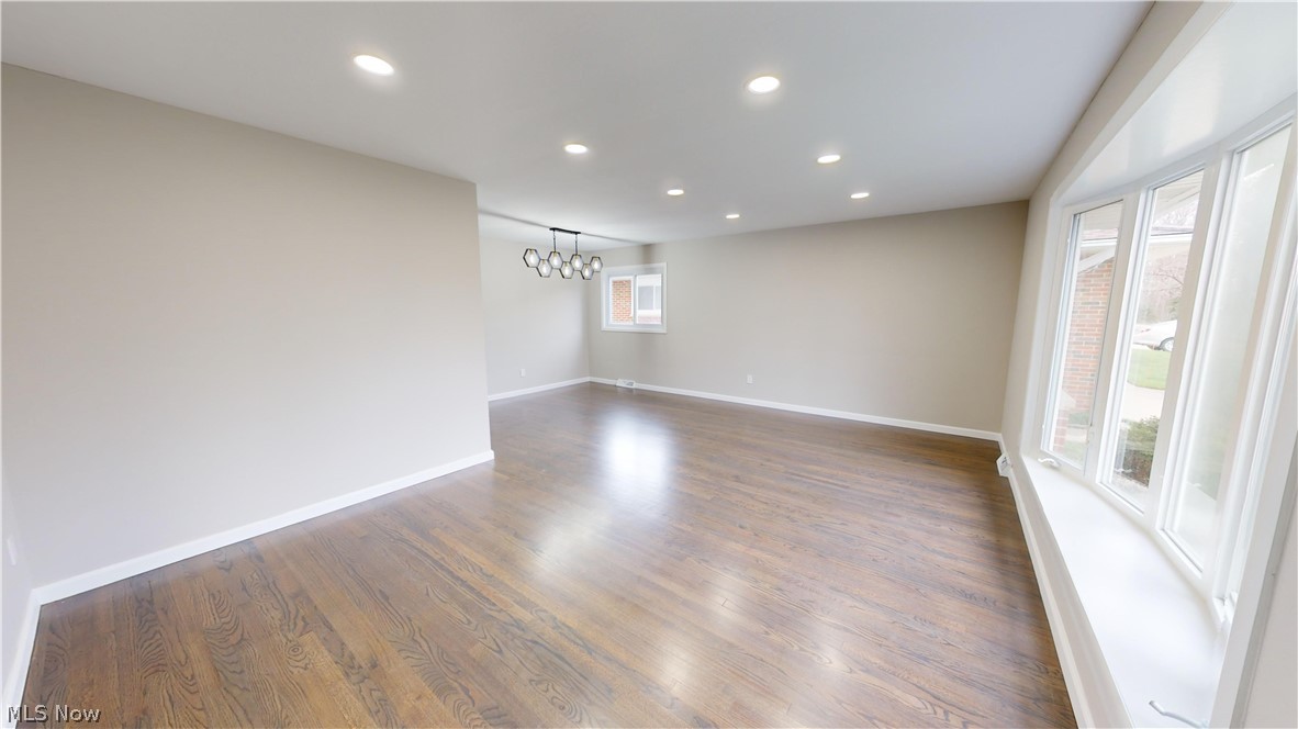1224 Cordova Road Mayfield Heights, OH 44124 - Photo 5 of 29 Empty room featuring a notable chandelier, dark hardwood / wood-style floors, and a wealth of natural light