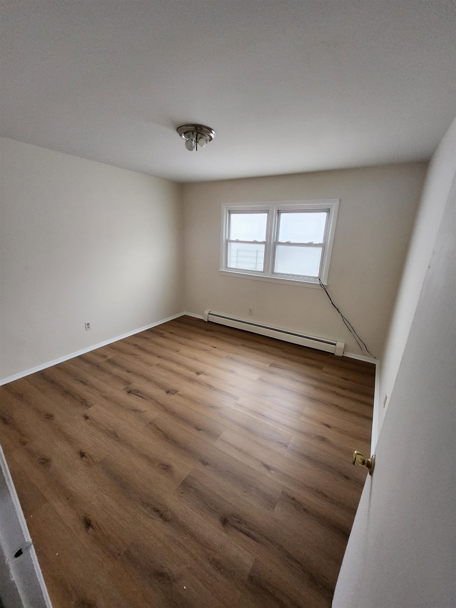 71 Linnet Street, Unit 2 Bayonne, NJ 07002 - Photo 13 of 18 an empty room with wooden floor and windows