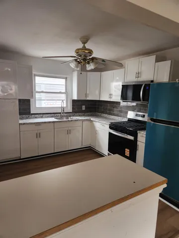 a kitchen with stainless steel appliances granite countertop a sink a stove a refrigerator a microwave oven with white cabinets