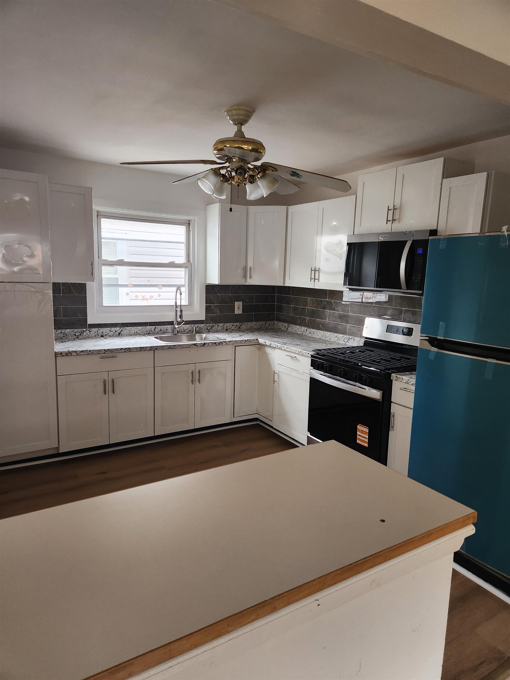 71 Linnet Street, Unit 2 Bayonne, NJ 07002 - Photo 7 of 18 a kitchen with stainless steel appliances granite countertop a sink a stove a refrigerator a microwave oven with white cabinets