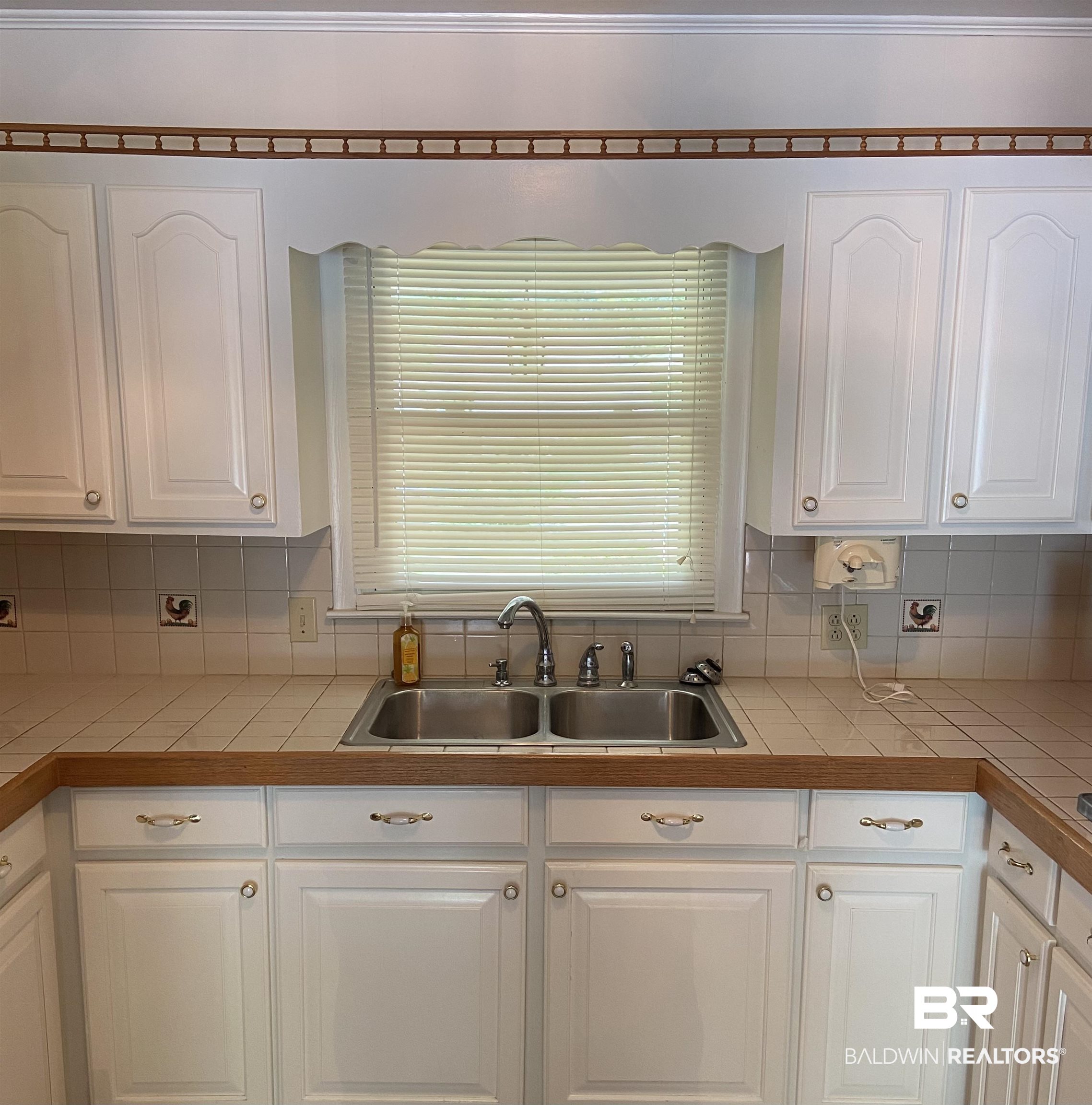 102 Ashley Street Evergreen, AL 36401 - Photo 4 of 26 Kitchen featuring sink, tile countertops, white cabinets, and backsplash