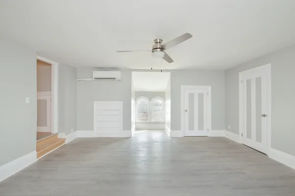 a view of empty room with wooden floor and ceiling fan