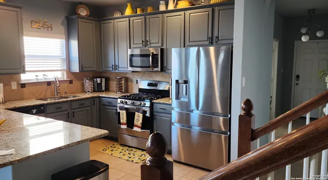 a kitchen with stainless steel appliances granite countertop a refrigerator a stove and a sink with wooden floor