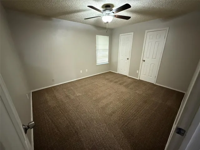 an empty room with windows and fan