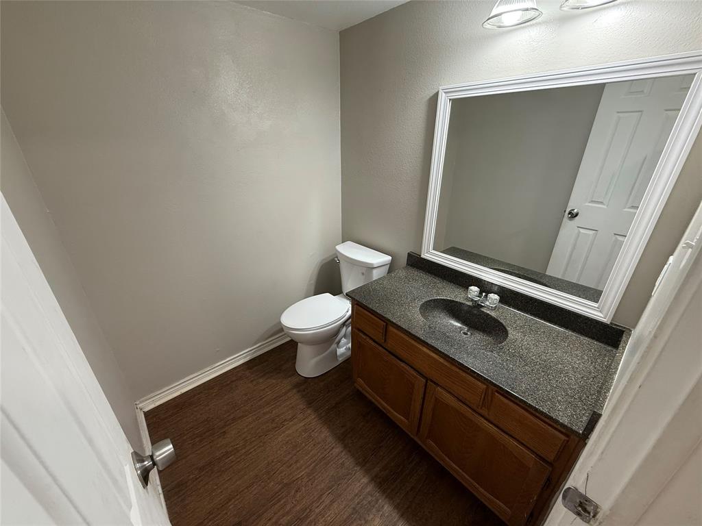 1610 Sun Valley Drive, Unit A Cleburne, TX 76033 - Photo 6 of 8 a bathroom with a granite countertop sink toilet and mirror