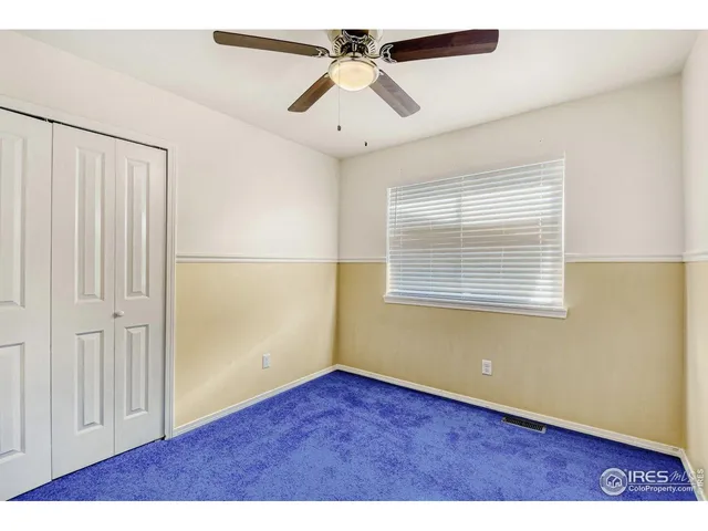 an empty room with wooden floor chandelier fan and windows