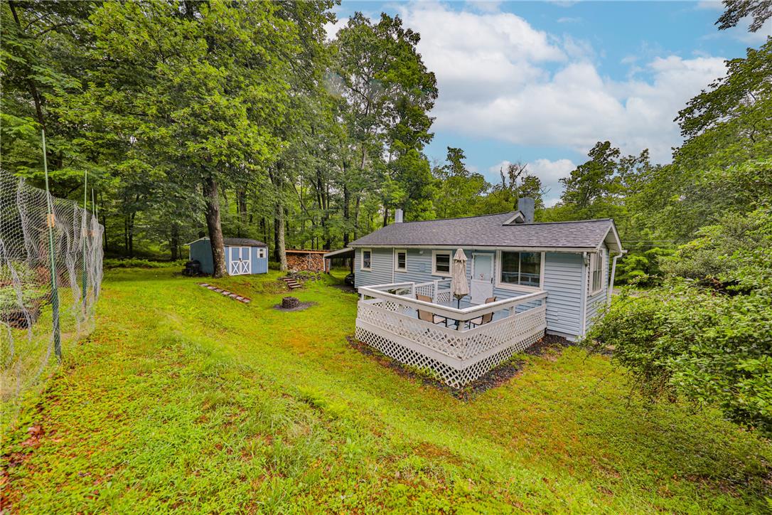 5599 Minks Pond Road Bushkill, PA 18324 - Photo 60 of 64 A tranquil woodland retreat featuring a charming residence with a spacious deck, ideal for outdoor enjoyment.