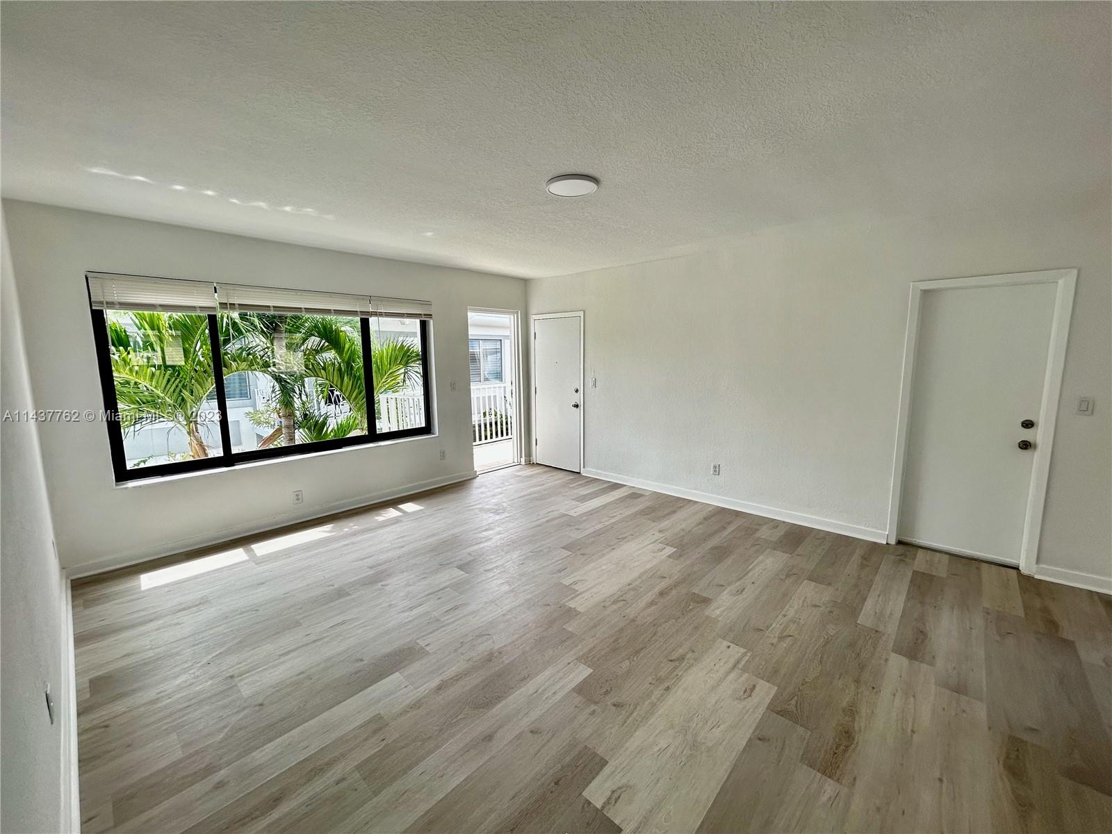 875 80th Street, Unit 3 Miami Beach, FL 33141 - Photo 10 of 15 an empty room with wooden floor and windows