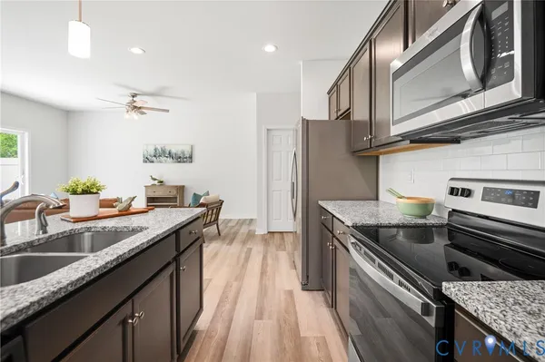 a kitchen with stainless steel appliances granite countertop a sink a stove and a wooden cabinets