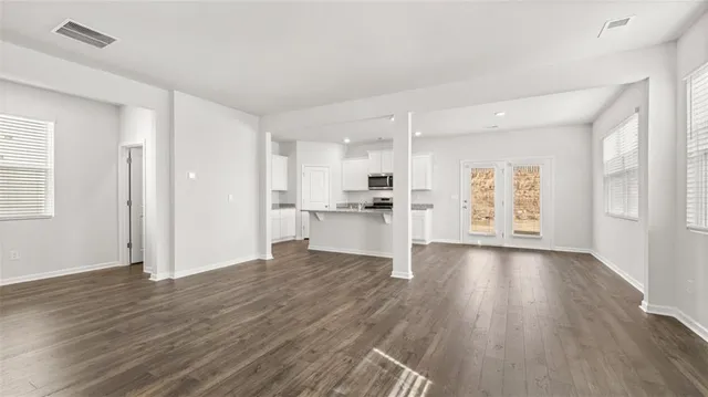 a view of an empty room with window and wooden floor