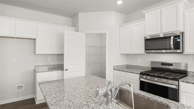 a kitchen with stainless steel appliances granite countertop a stove a sink and a microwave