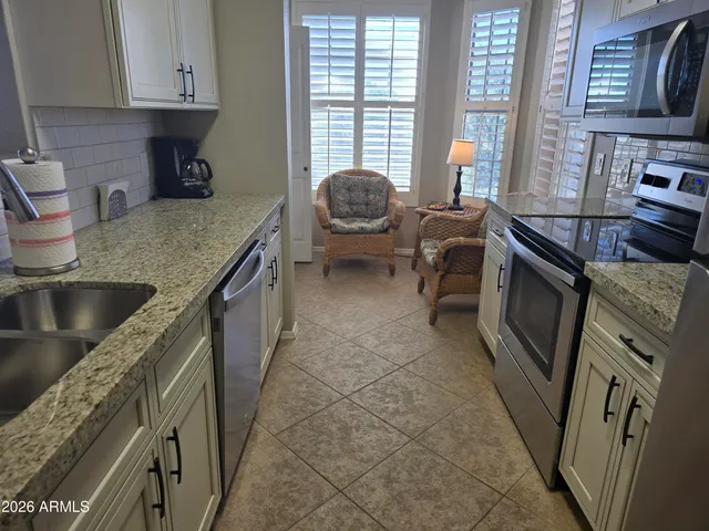 a kitchen with granite countertop a stove a sink and a refrigerator