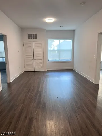 an empty room with wooden floor cabinet and windows