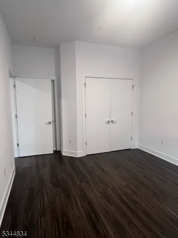 a view of an empty room with wooden floor and white doors