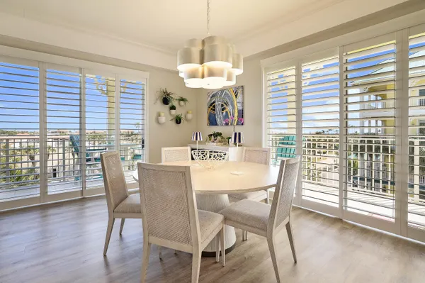 a dining room with wooden floor a chandelier a glass table and chairs