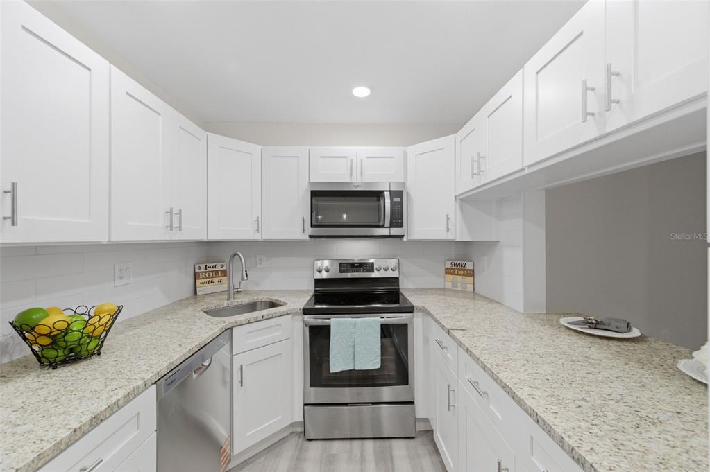 1135 Pine Ridge Circle West, Unit A2 Tarpon Springs, FL 34688 - Photo 15 of 63 a kitchen with granite countertop a stove sink and cabinets