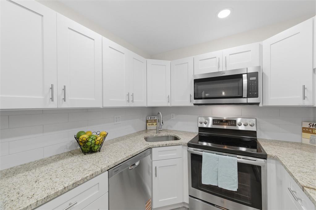1135 Pine Ridge Circle West, Unit A2 Tarpon Springs, FL 34688 - Photo 16 of 63 a kitchen with stainless steel appliances granite countertop a sink a stove a microwave and cabinets