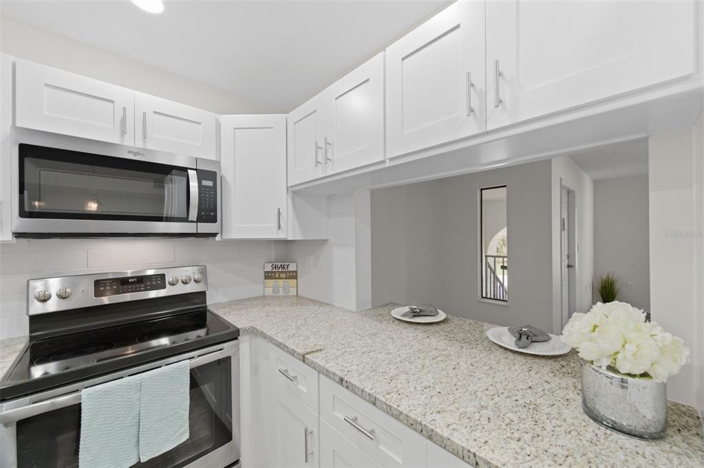 1135 Pine Ridge Circle West, Unit A2 Tarpon Springs, FL 34688 - Photo 17 of 63 a kitchen with stainless steel appliances granite countertop a sink and a stove