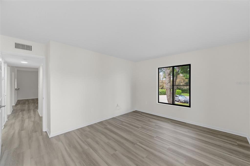 1135 Pine Ridge Circle West, Unit A2 Tarpon Springs, FL 34688 - Photo 27 of 63 an empty room with wooden floor and windows