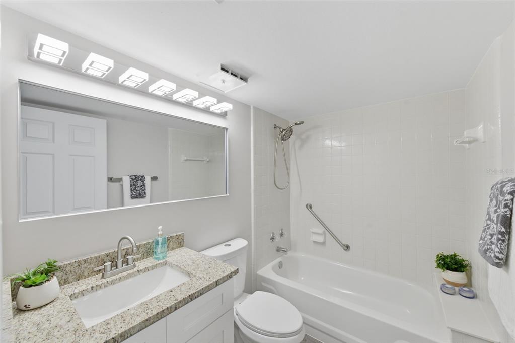 1135 Pine Ridge Circle West, Unit A2 Tarpon Springs, FL 34688 - Photo 35 of 63 a bathroom with a granite countertop sink vanity mirror bathtub shower and a toilet