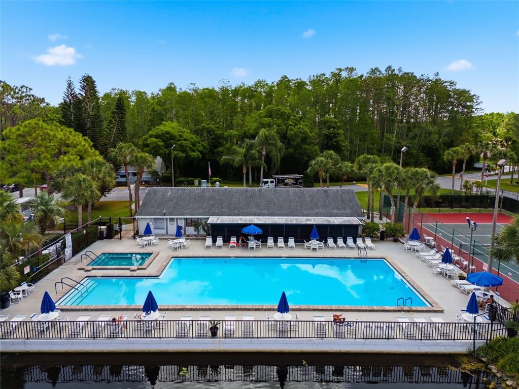 1135 Pine Ridge Circle West, Unit A2 Tarpon Springs, FL 34688 - Photo 54 of 63 a view of a tennis ground with large trees and wooden fence
