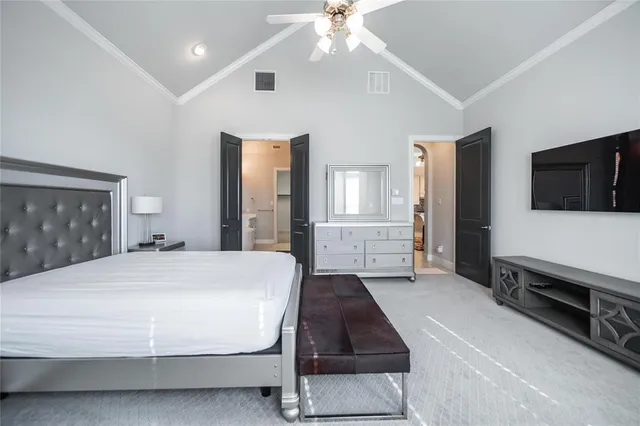 a spacious bedroom with a bed and a flat tv screen on dresser