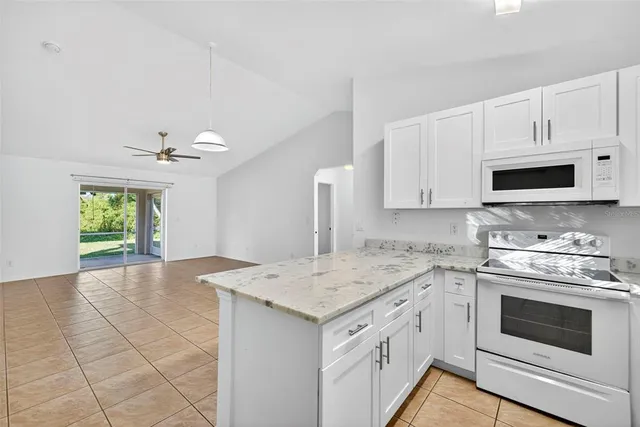 a kitchen with granite countertop a stove sink and microwave