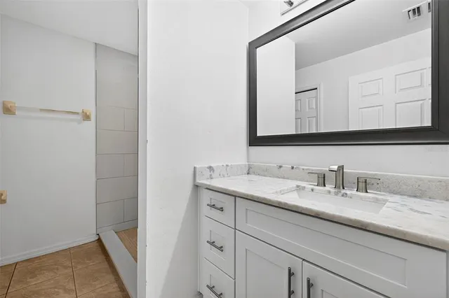 a bathroom with a granite countertop sink and a mirror