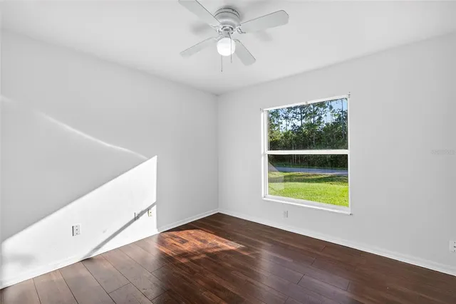 a view of an empty room with window and wooden floor